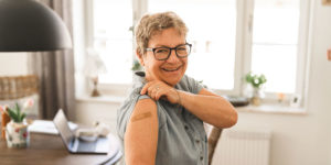 Smiling senior woman shows her band aide after getting a flu shot