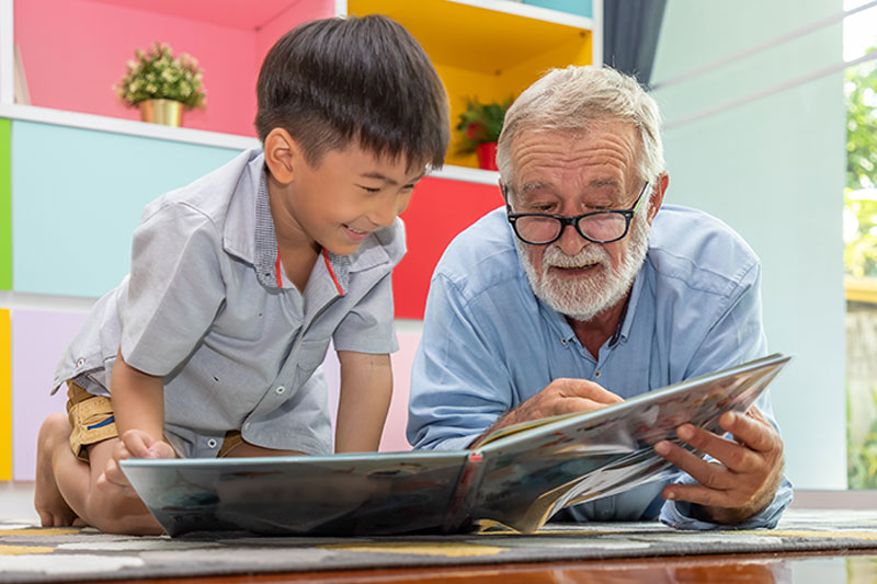 grandchild-and-senior-grandpa-reading-book
