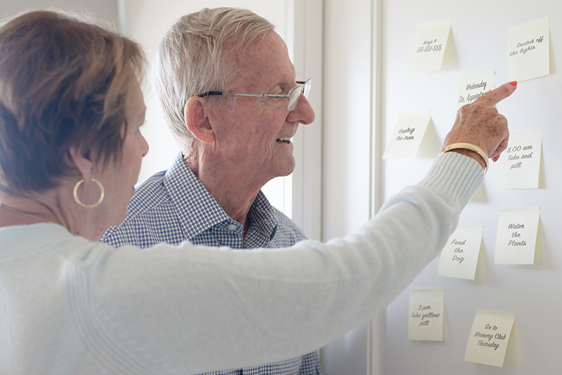 woman pointing to post-it notes with senior man