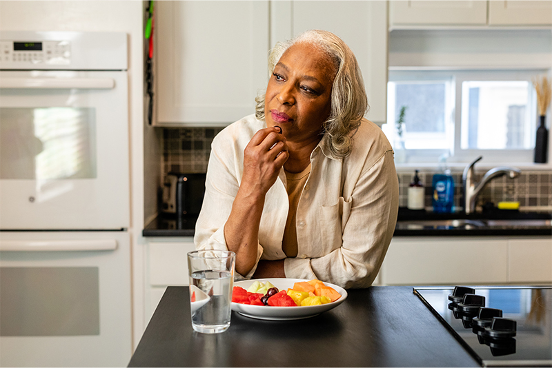 Senior woman in her kitchen eating a healthy snack