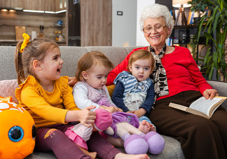 Grandmother reading with 3 grandkids on the couch