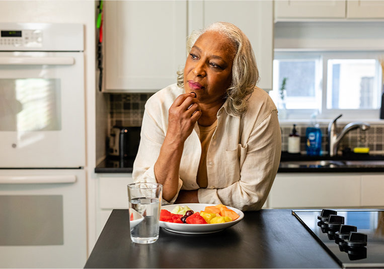 Senior woman in her kitchen eating a healthy snack